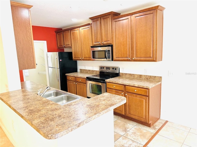 kitchen featuring sink, light tile patterned floors, kitchen peninsula, and appliances with stainless steel finishes