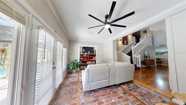 living area with brick floor, a ceiling fan, ornamental molding, and stairs