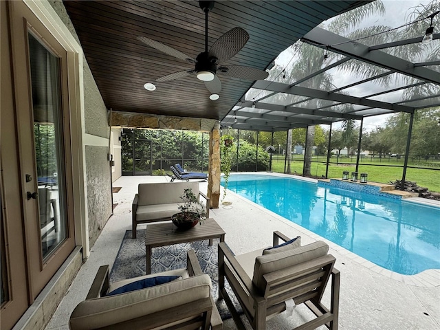 outdoor pool with glass enclosure, outdoor lounge area, a ceiling fan, a yard, and a patio area