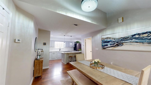 dining space with dark wood-style floors, visible vents, and baseboards