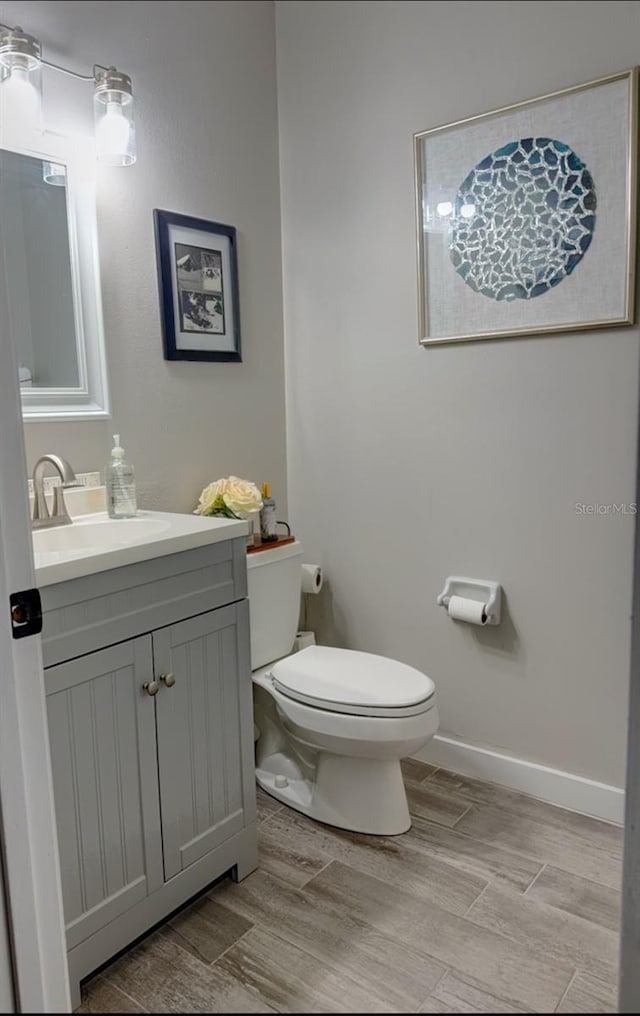 bathroom with vanity, wood finished floors, toilet, and baseboards