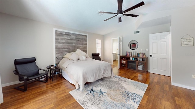 bedroom featuring baseboards, visible vents, a ceiling fan, lofted ceiling, and wood finished floors