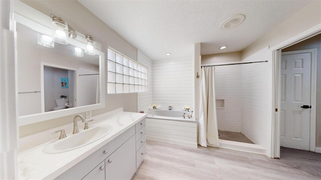 bathroom with hardwood / wood-style floors, vanity, separate shower and tub, and a textured ceiling