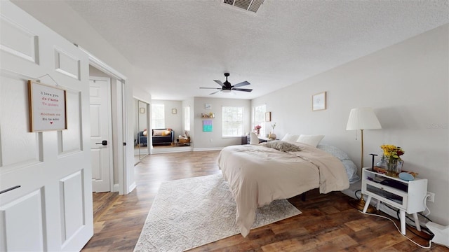 bedroom with ceiling fan, dark hardwood / wood-style flooring, and a textured ceiling