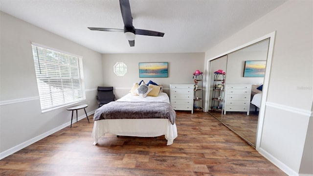 bedroom featuring a ceiling fan, a closet, baseboards, and wood finished floors