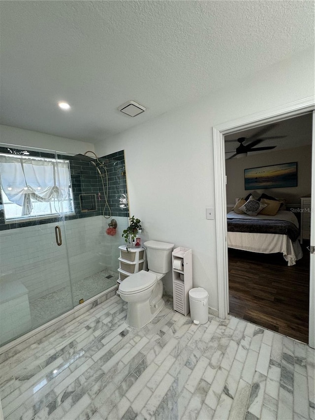 bathroom with ceiling fan, toilet, an enclosed shower, and a textured ceiling