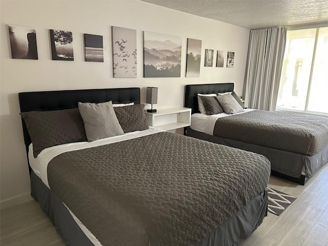 bedroom featuring a textured ceiling, wood finished floors, and baseboards