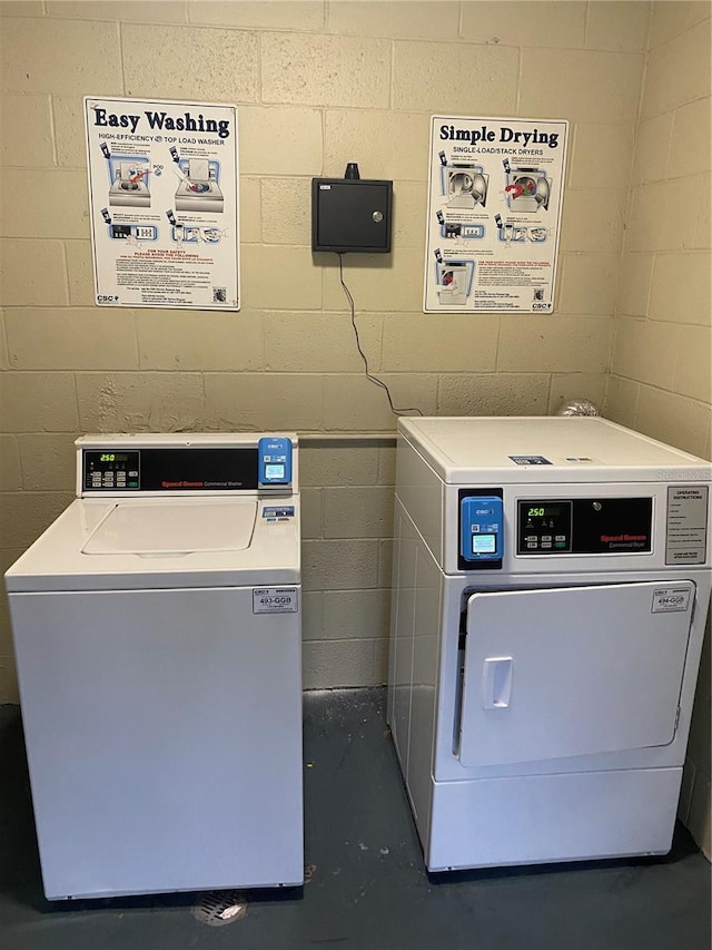 community laundry room featuring washer / dryer and concrete block wall