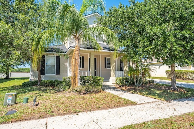 view of property hidden behind natural elements with a front lawn and covered porch