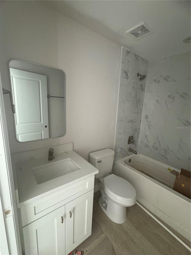 full bathroom featuring vanity, tiled shower / bath combo, toilet, and hardwood / wood-style floors