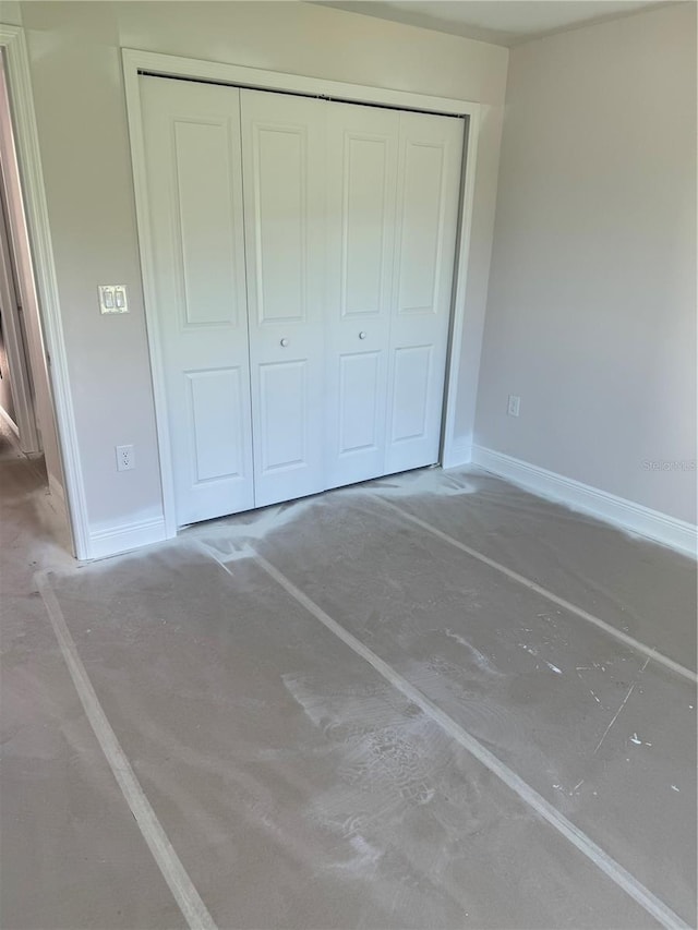 unfurnished bedroom featuring concrete floors and a closet