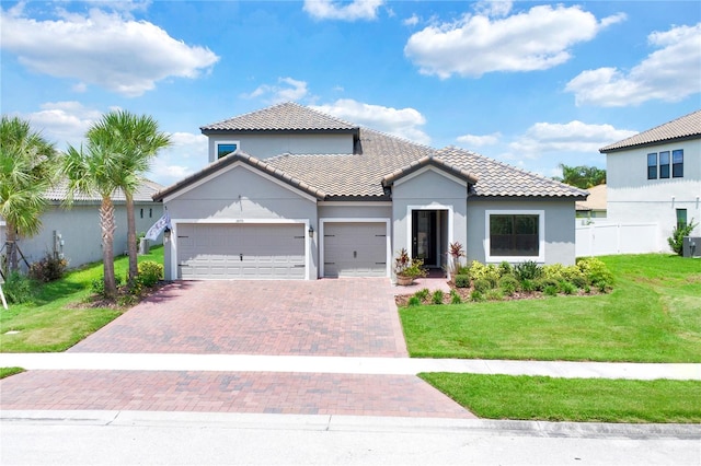 mediterranean / spanish home featuring a garage and a front lawn