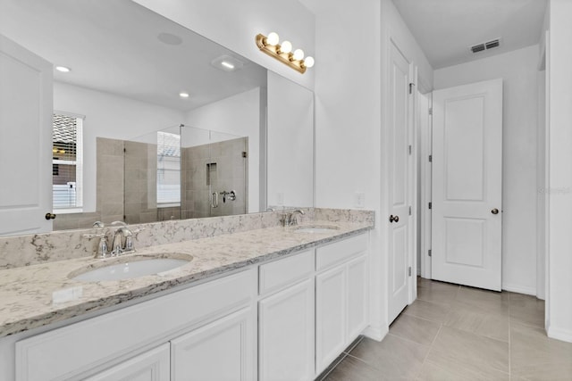 bathroom with tiled shower, vanity, and tile patterned flooring