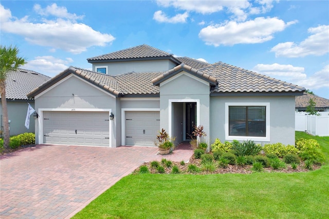 mediterranean / spanish house with a garage and a front lawn