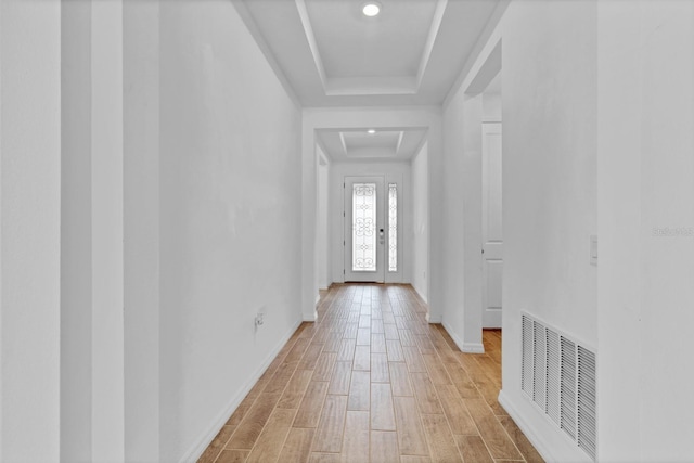 corridor with hardwood / wood-style flooring and a raised ceiling