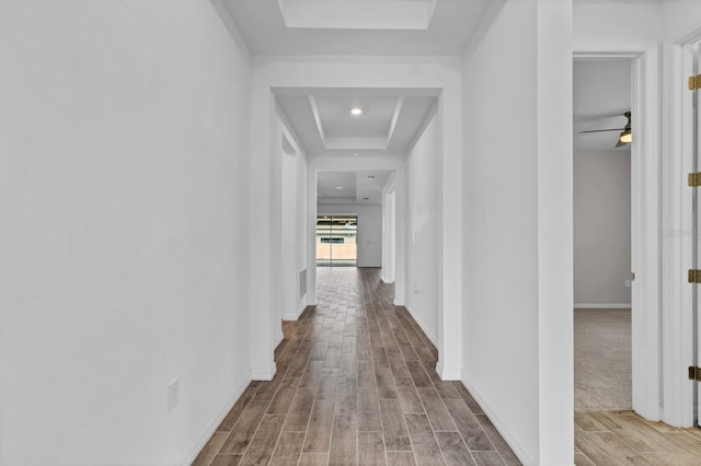 hall featuring hardwood / wood-style flooring and a tray ceiling