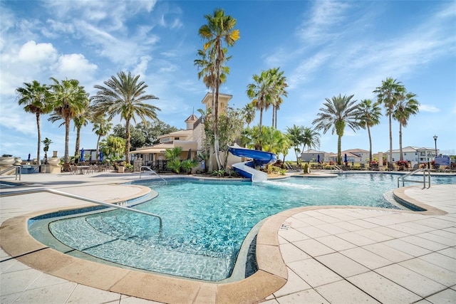 view of pool with a water slide and a patio