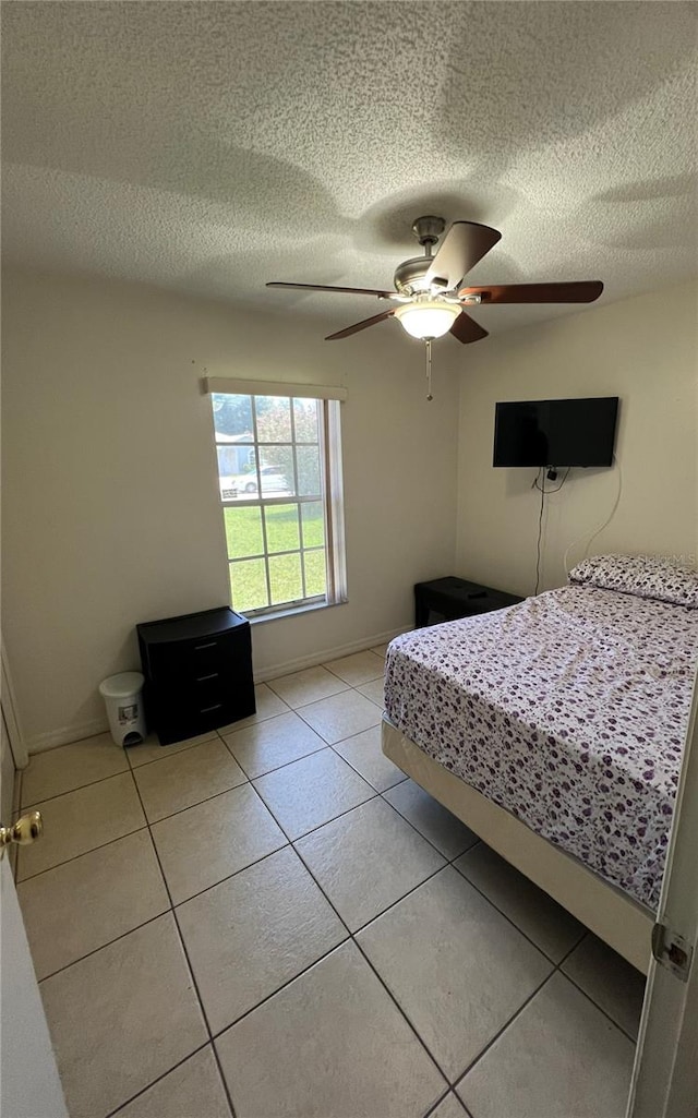 unfurnished bedroom featuring a textured ceiling, ceiling fan, and light tile patterned floors