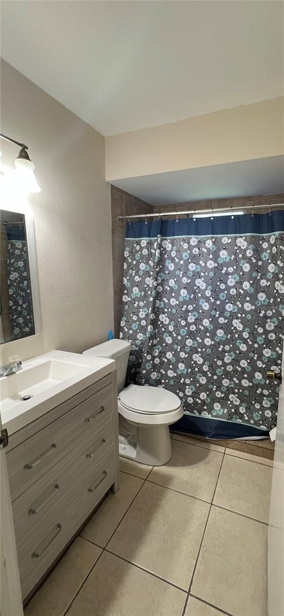 bathroom featuring tile patterned flooring, toilet, walk in shower, and vanity