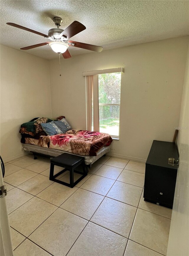 bedroom with a textured ceiling, ceiling fan, and light tile patterned floors