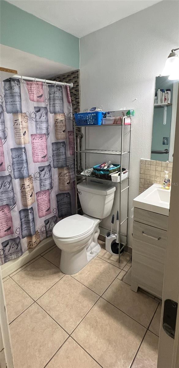 bathroom with tile patterned flooring, vanity, toilet, and walk in shower