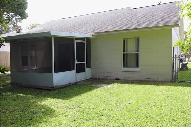 rear view of house featuring a sunroom and a lawn