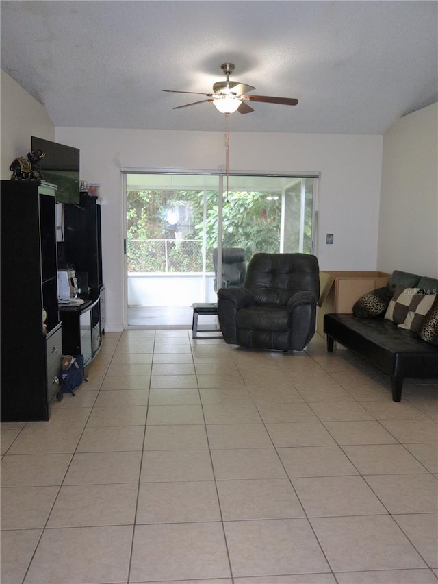 living room with ceiling fan, light tile patterned floors, and a textured ceiling