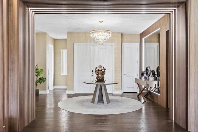 foyer entrance with dark hardwood / wood-style flooring and an inviting chandelier