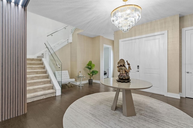 entrance foyer with dark hardwood / wood-style floors, a textured ceiling, and an inviting chandelier