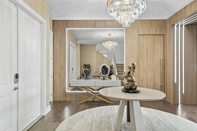 dining room featuring dark hardwood / wood-style flooring, wooden walls, and an inviting chandelier