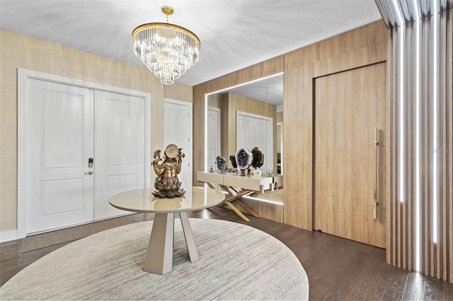 foyer entrance with a textured ceiling, an inviting chandelier, and dark wood-type flooring