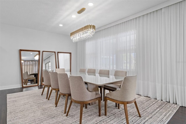 dining space with hardwood / wood-style flooring, a textured ceiling, and an inviting chandelier