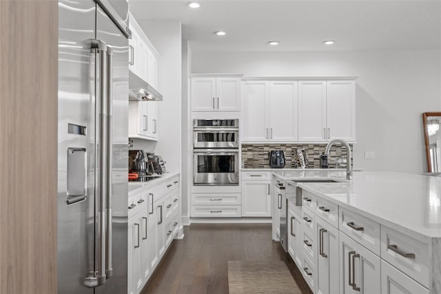 kitchen with white cabinetry, appliances with stainless steel finishes, dark wood-type flooring, and tasteful backsplash