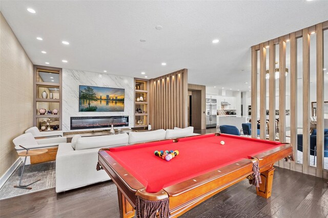 game room with built in shelves, pool table, dark wood-type flooring, and a premium fireplace