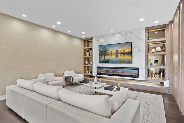 living room with dark wood-type flooring, a premium fireplace, built in features, and a textured ceiling