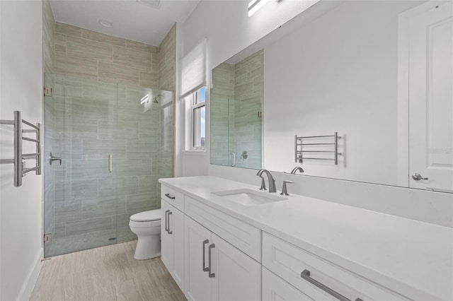 bathroom featuring a shower with door, toilet, and vanity