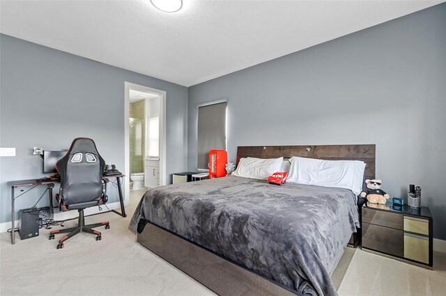 bedroom with connected bathroom and light colored carpet