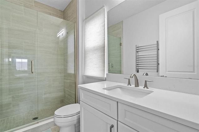 bathroom featuring a shower with door, vanity, radiator, and toilet