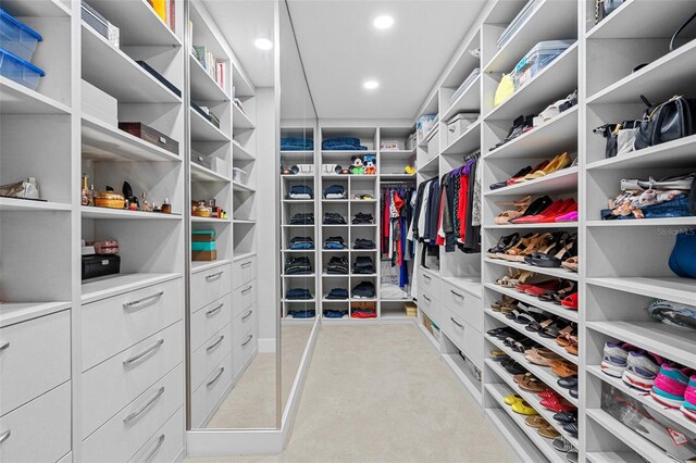 walk in closet featuring light colored carpet