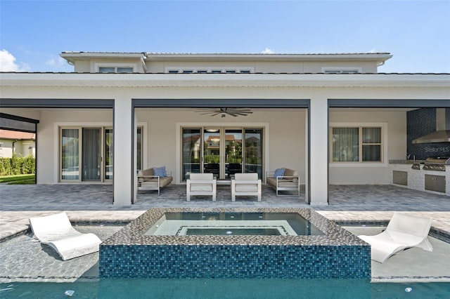 rear view of house with an outdoor living space, a patio area, exterior kitchen, and an in ground hot tub