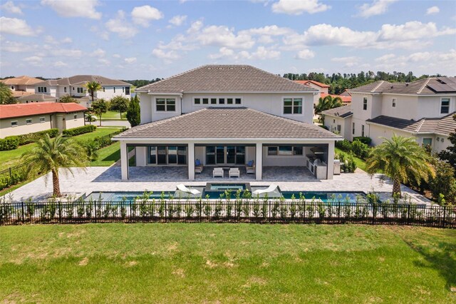 rear view of house featuring a patio, a yard, and a swimming pool with hot tub