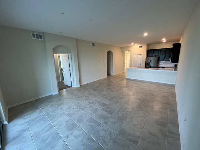 unfurnished living room featuring sink and light tile patterned floors