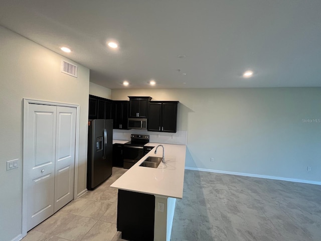 kitchen with a kitchen island with sink, light tile patterned floors, sink, and black appliances