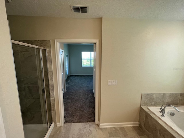 bathroom featuring shower with separate bathtub, tile patterned floors, and a textured ceiling