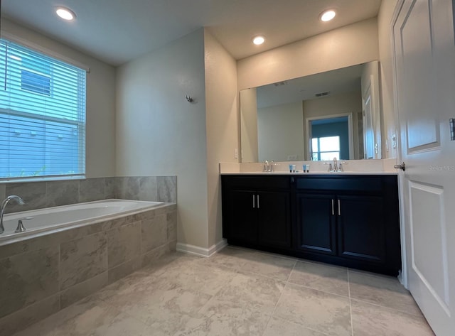 bathroom featuring a relaxing tiled tub, vanity, and tile patterned floors