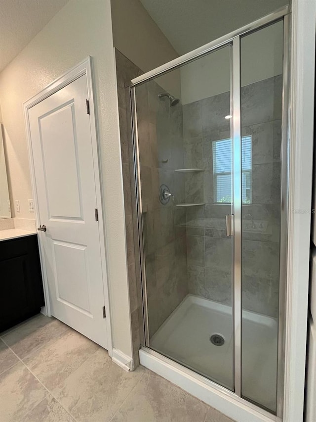 bathroom with a shower with door, vanity, and tile patterned flooring