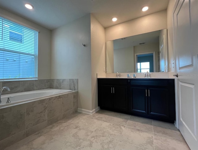 bathroom with tile patterned floors, vanity, and tiled bath