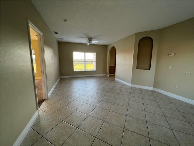 unfurnished room with ceiling fan, light tile patterned floors, and a textured ceiling