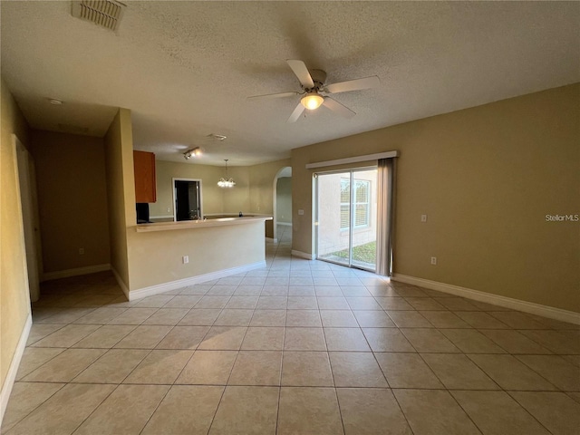 unfurnished living room featuring a textured ceiling, ceiling fan with notable chandelier, and light tile patterned flooring