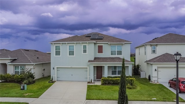 front of property featuring solar panels, a front yard, and a garage